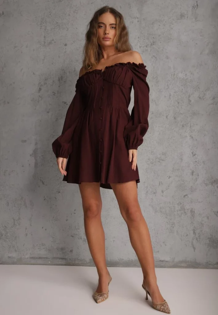 Modelka prezentuje brązową sukienkę hiszpankę mini w rustykalnym stylu.