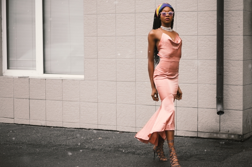 Modelka prezentuje dopasowaną brzoskwiniową sukienkę.