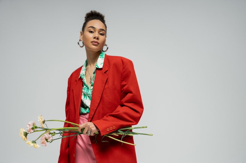 Modelka prezentuje stylizacje z koszulą w kwiaty i czerwoną marynarką.