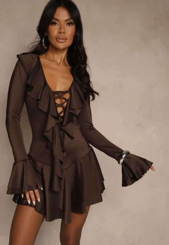 Modelka prezentuje brązową sukienkę mini z falbankami i gorsetowym wiązaniem.