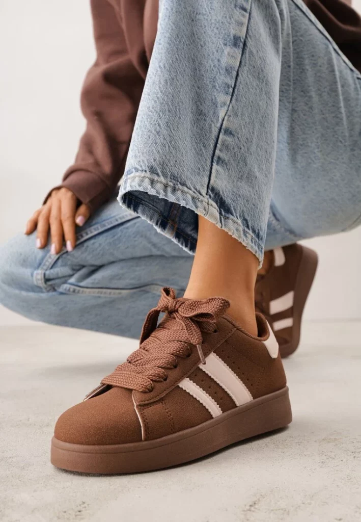 Brązowo-białe sneakersy na niskiej platformie z naszywkami.