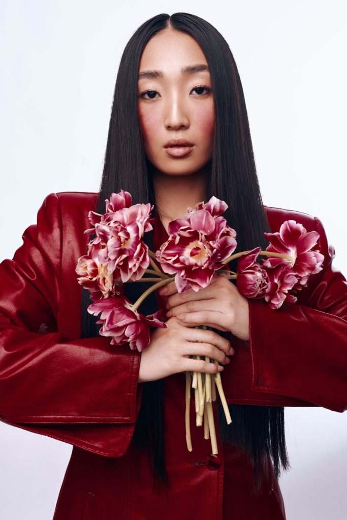 Romantyczny makijaż na walentynki w stylu coquette z różem na policzkach w stylizacji z bordową marynarką.